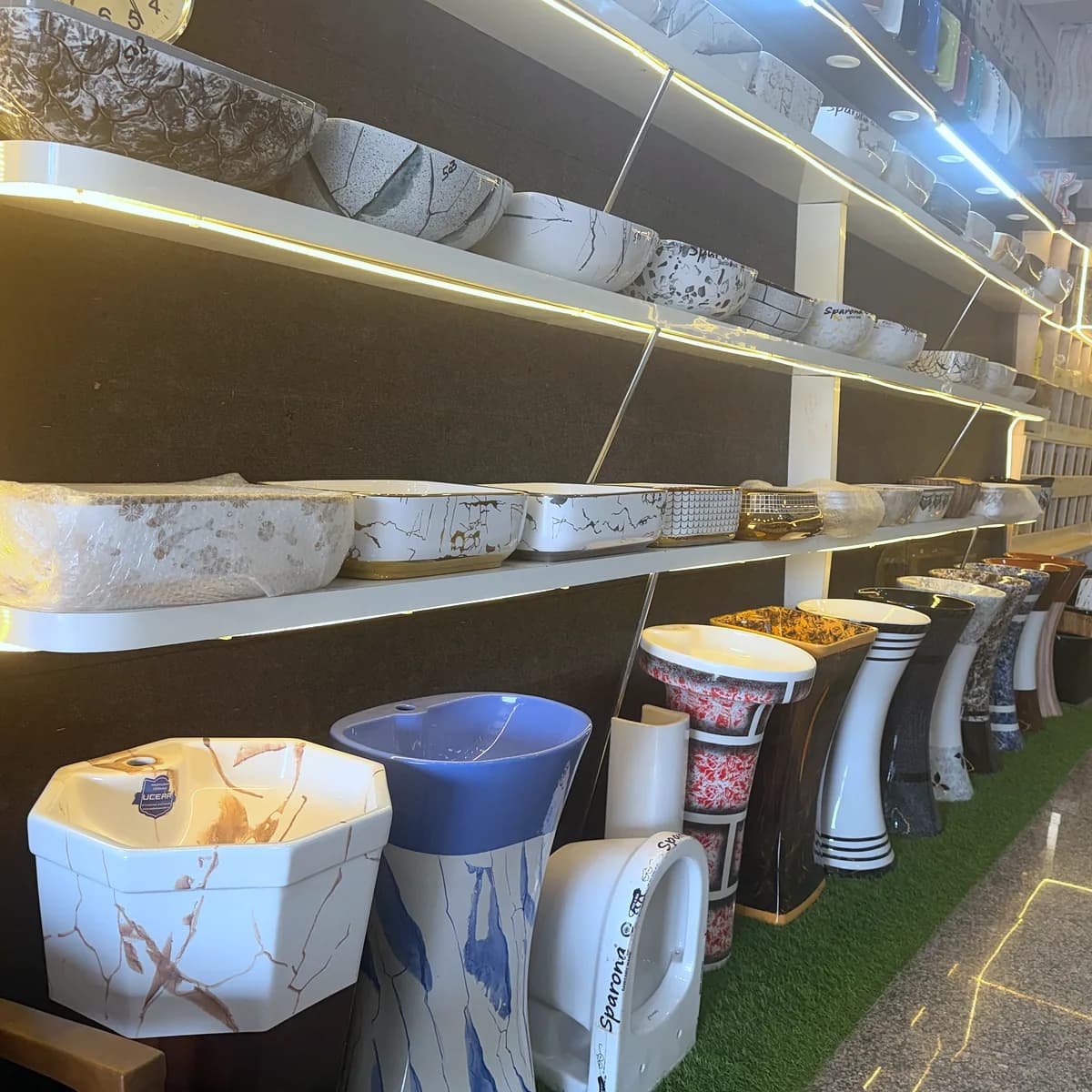 Illuminated shelves of counter-top basins above a row of pedestal basins