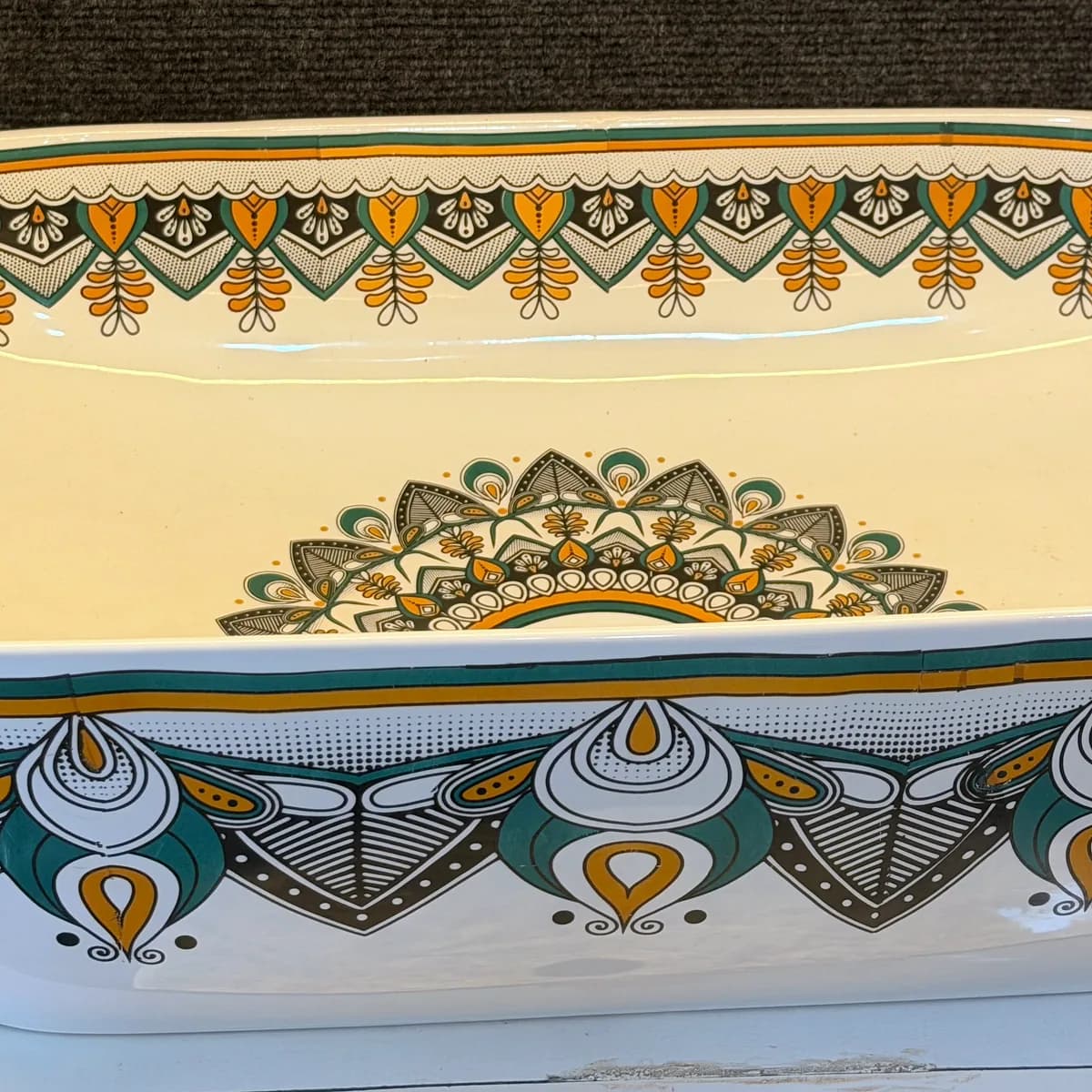 A cream counter-top basin decorated with a green and gold mandala pattern