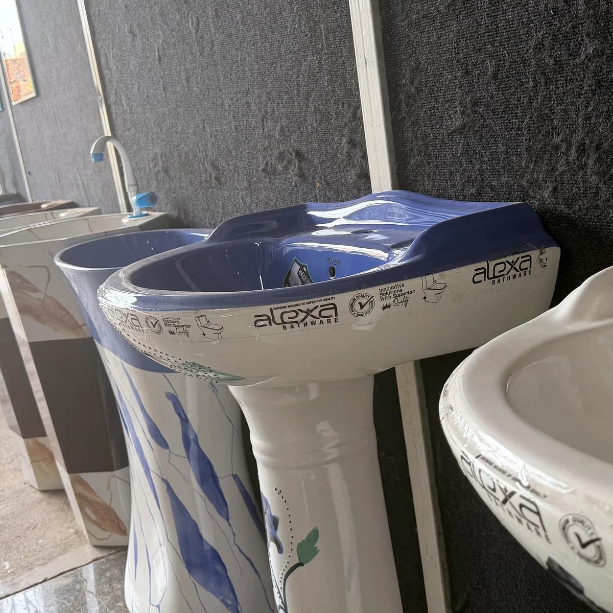 Blue and white pedestal wash basins arranged along the display wall