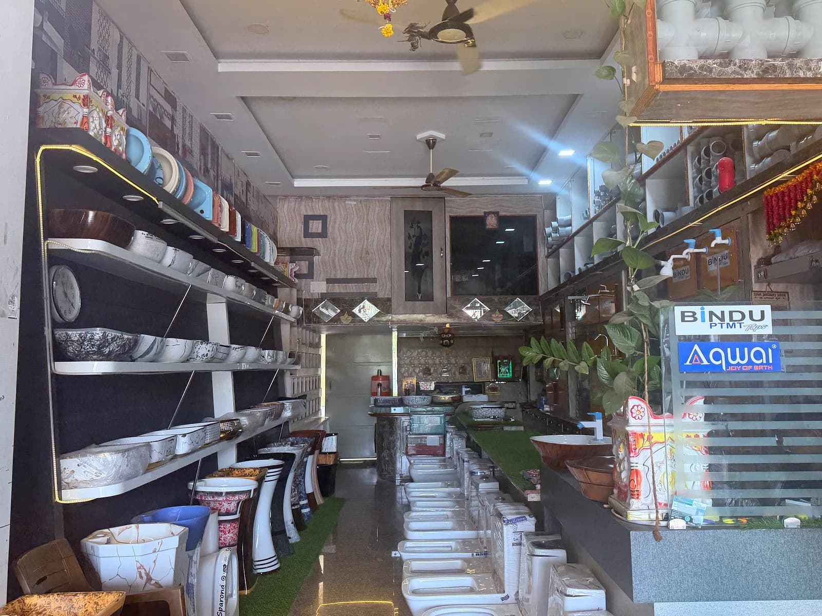 The main aisle of the Mathaji Ceramics showroom, lined with display shelves of wash basins and sanitaryware